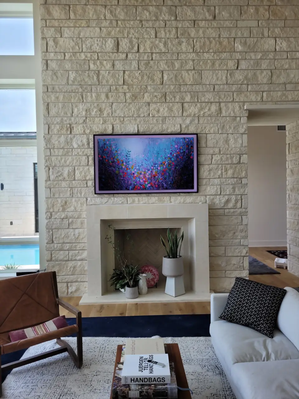 Samsung Frame TV displaying vibrant art on a cream Austin limestone fireplace wall in a designer living room