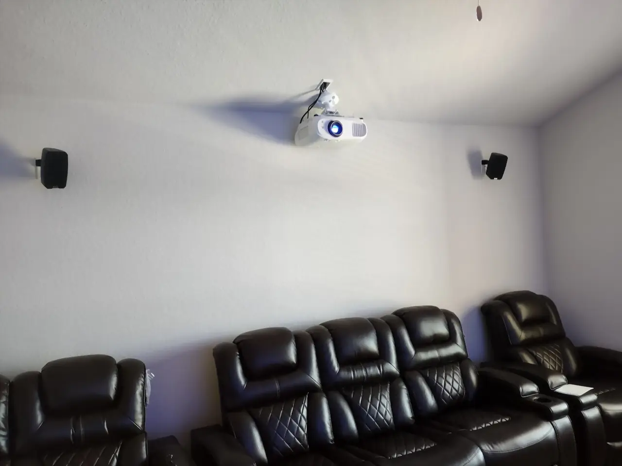 Media room with a wall-mounted projector, surround speakers and leather recliners