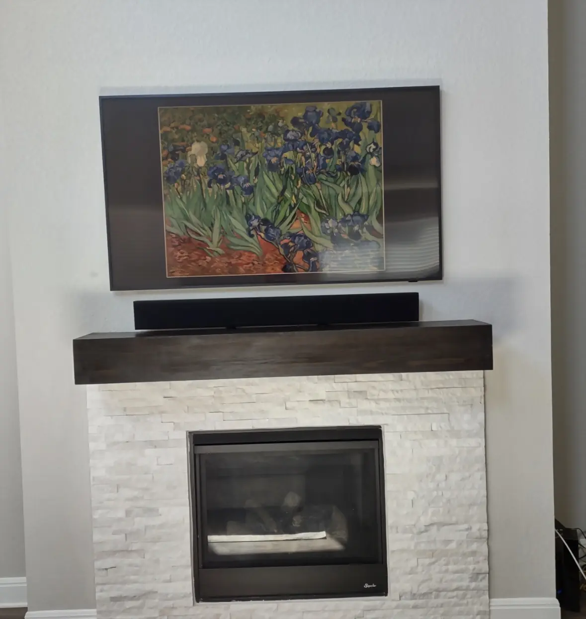 Samsung Frame TV displaying Van Gogh irises above a white ledgestone fireplace