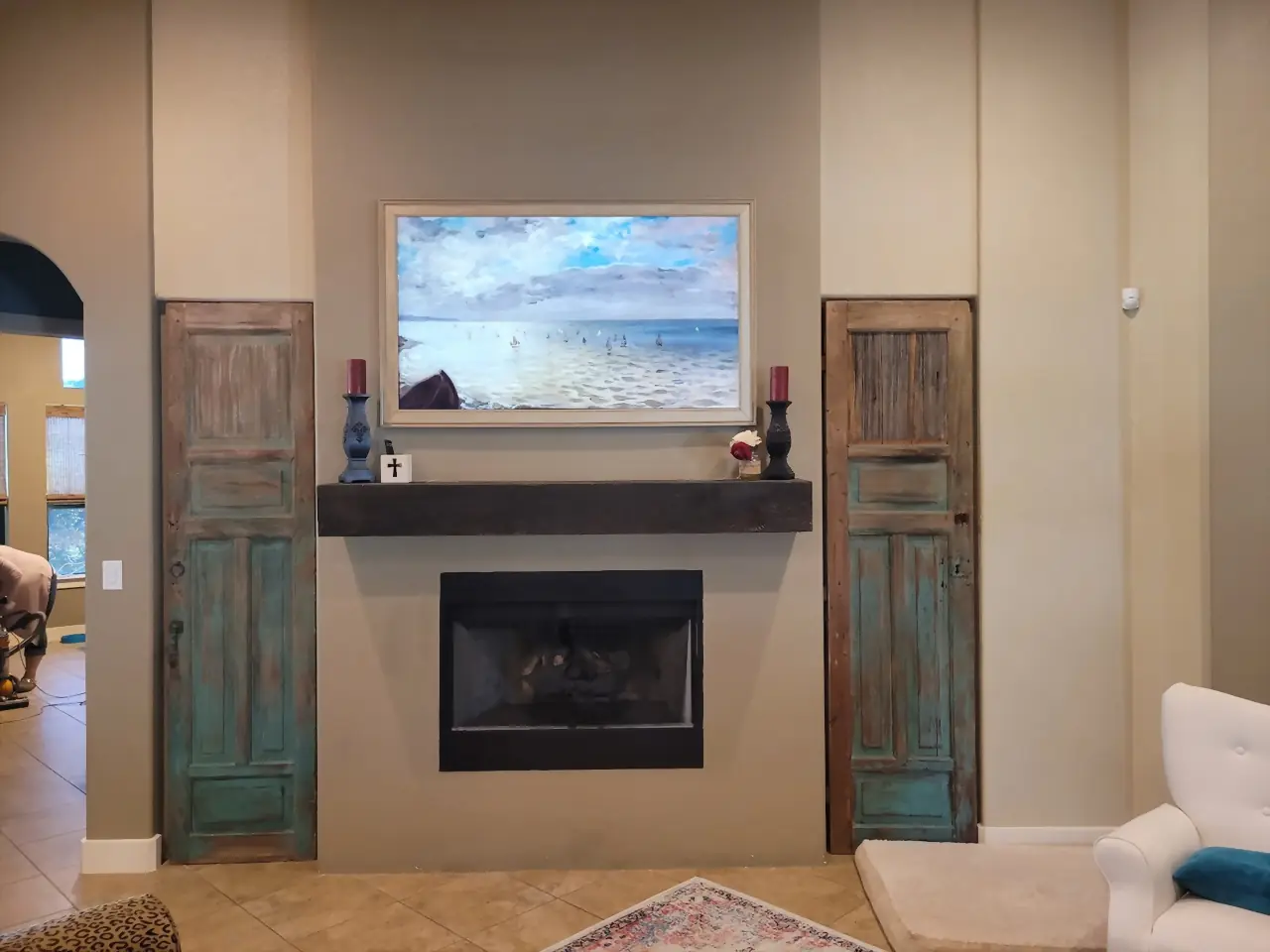 Samsung Frame TV showing a seascape above a chunky rustic mantel styled with candles