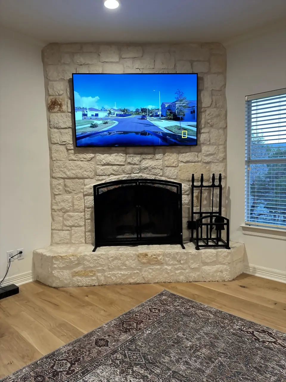 TV mounted on a white Austin limestone corner fireplace in a styled living room