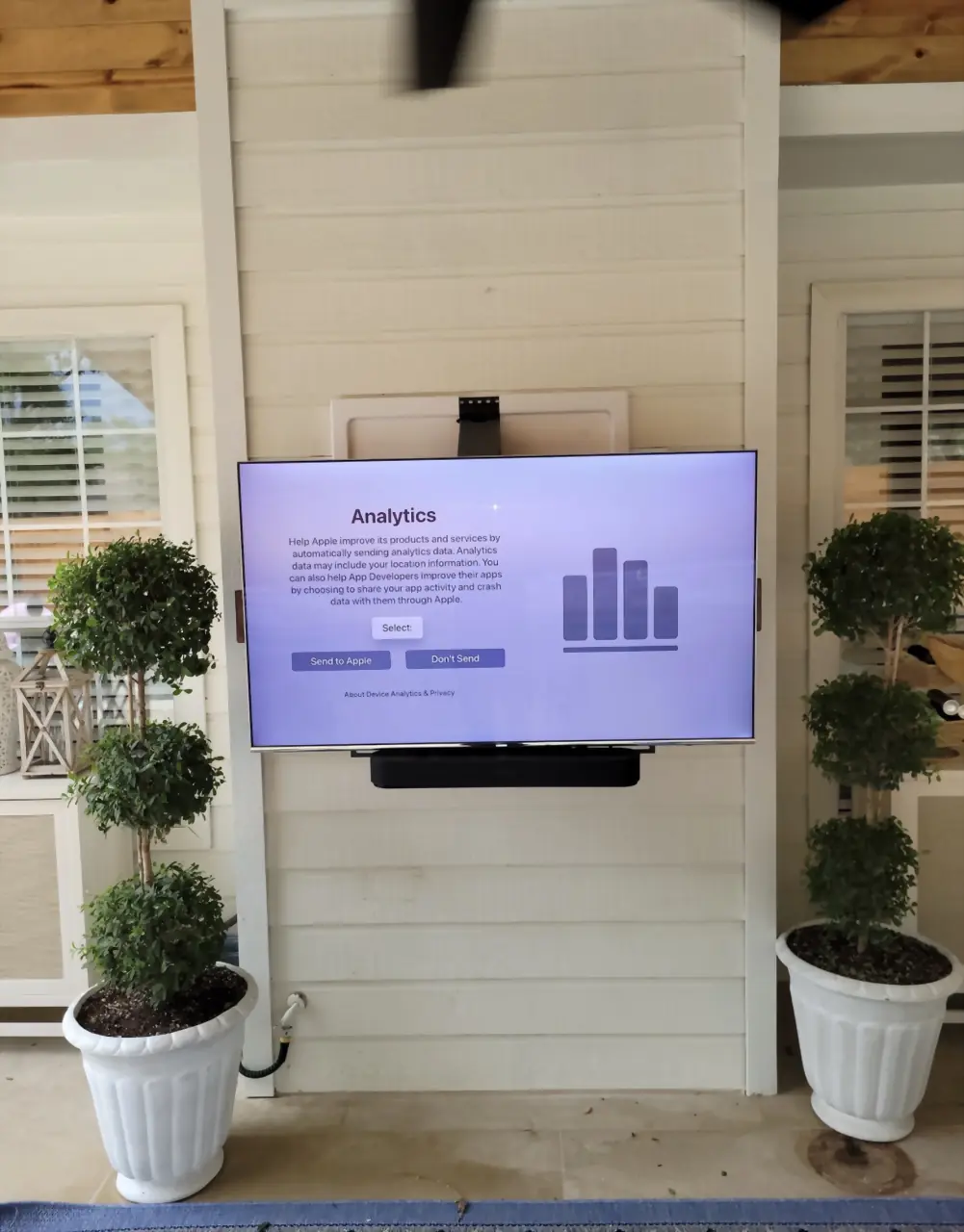 The same outdoor TV pulled down and forward on its mantel mount to eye level