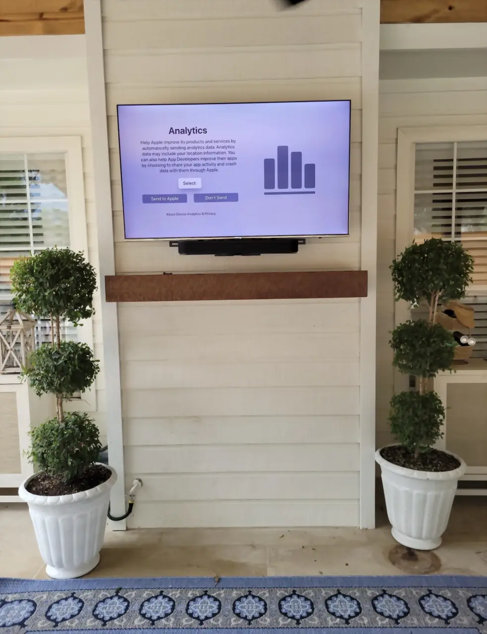 Outdoor TV and soundbar tucked up on the wall above a mantel-mount bracket