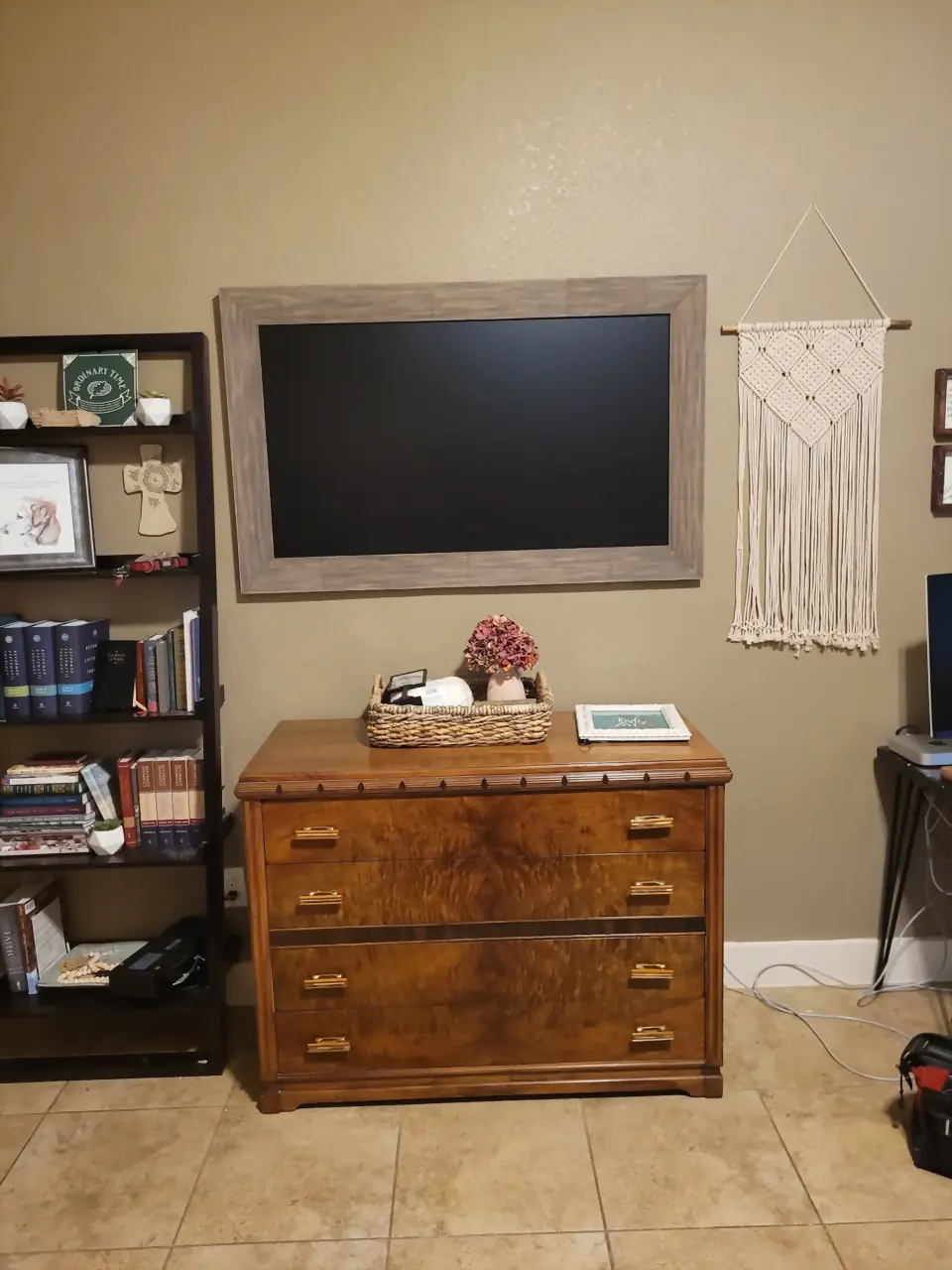 TV in a custom rustic wood frame mounted above a styled antique dresser