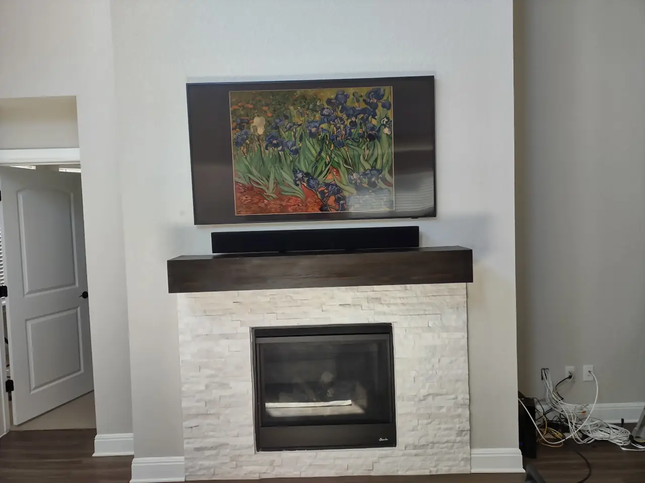 Samsung Frame TV showing Van Gogh irises with a soundbar on a white stacked-stone fireplace