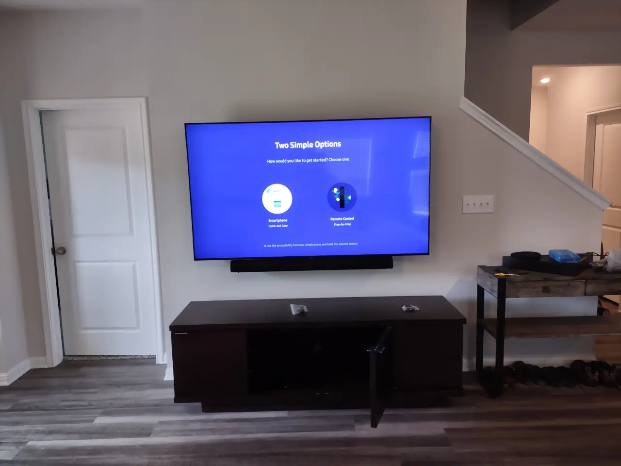 TV and soundbar mounted over a dark console beside a staircase