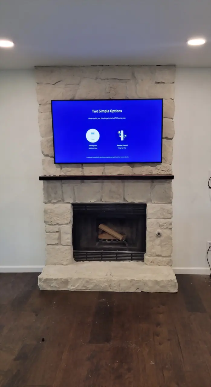 White rough-cut stone fireplace with a TV mounted above a dark wood mantel