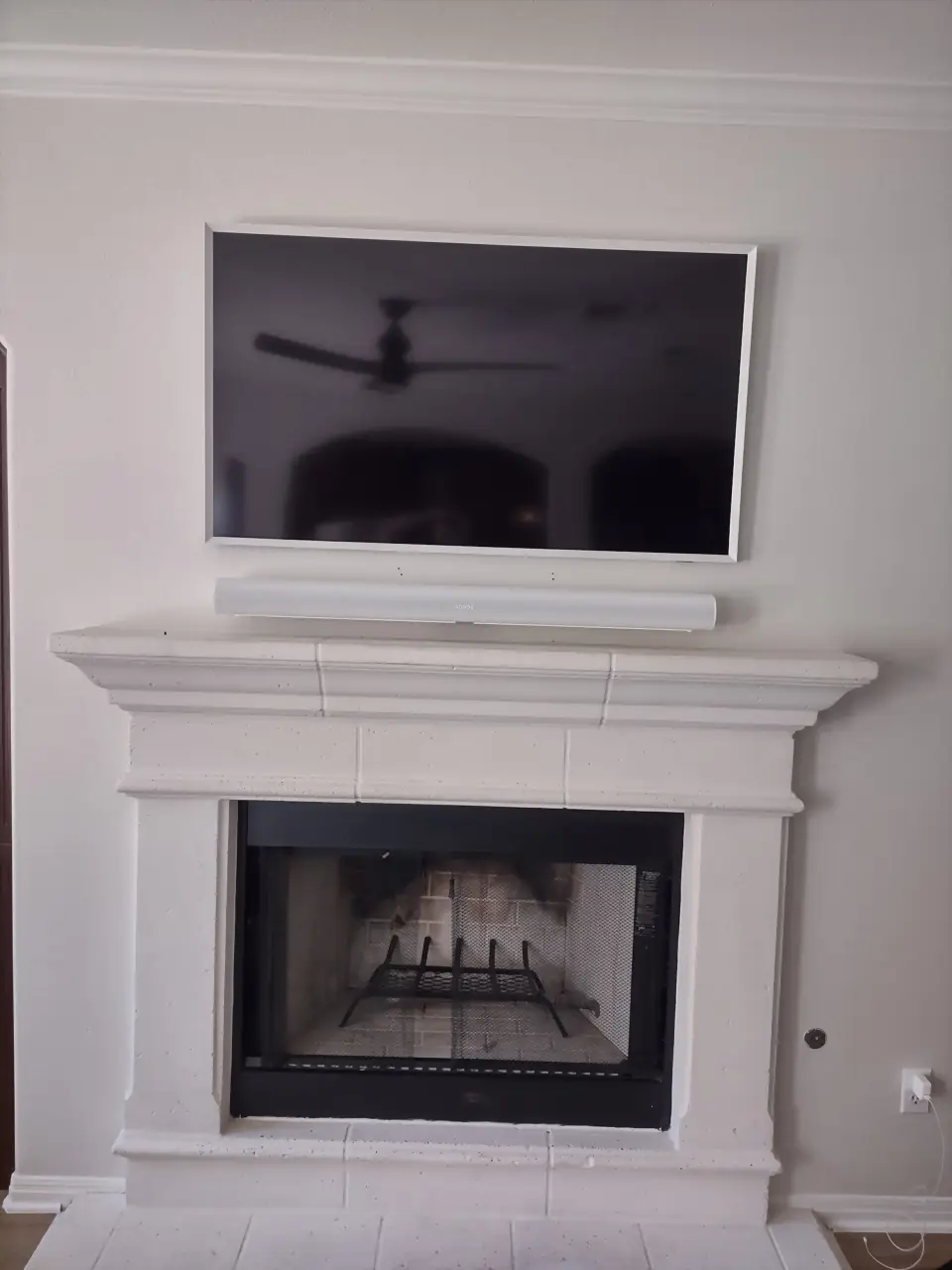 TV with a white Sonos Arc soundbar above a white cast-stone mantel