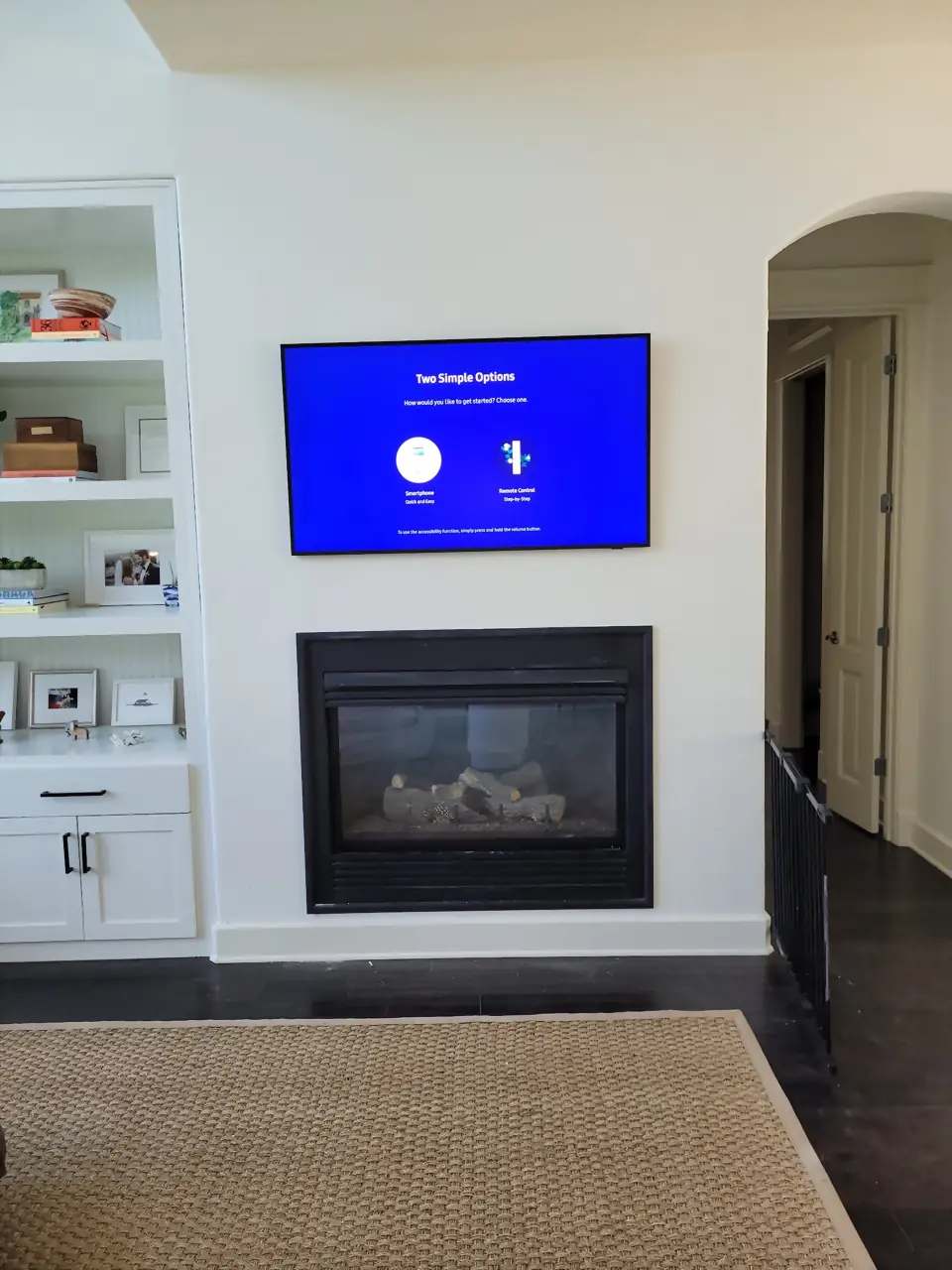 TV mounted above a black fireplace insert on a white wall with built-ins to the left