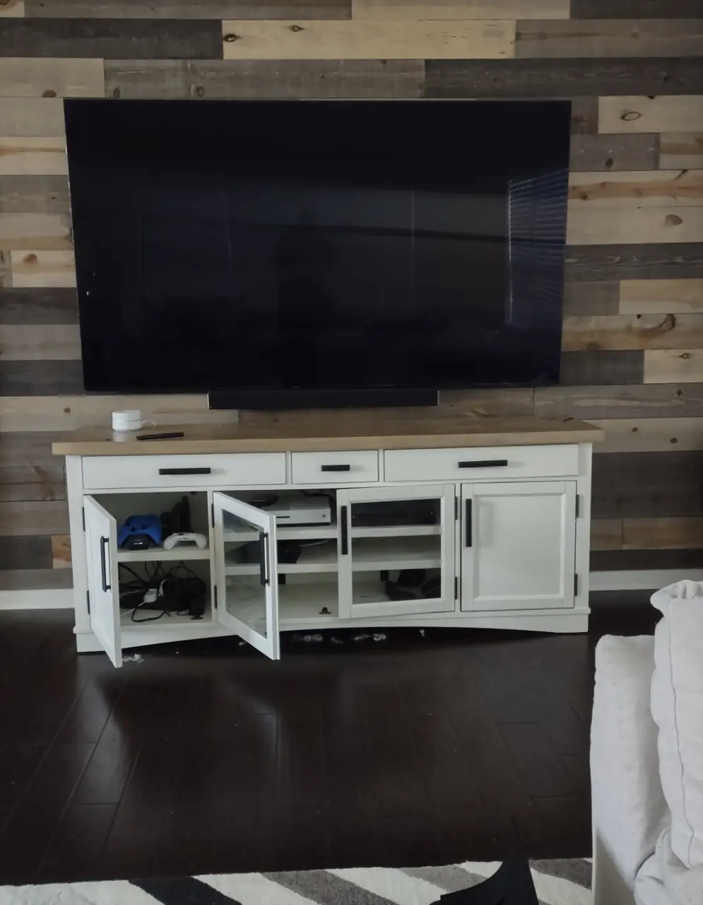 TV and soundbar mounted on a reclaimed wood plank wall above a white media console